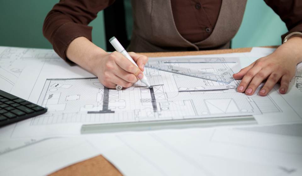 Architect working on blueprints on her desk. Working on new projects. Architecture and design